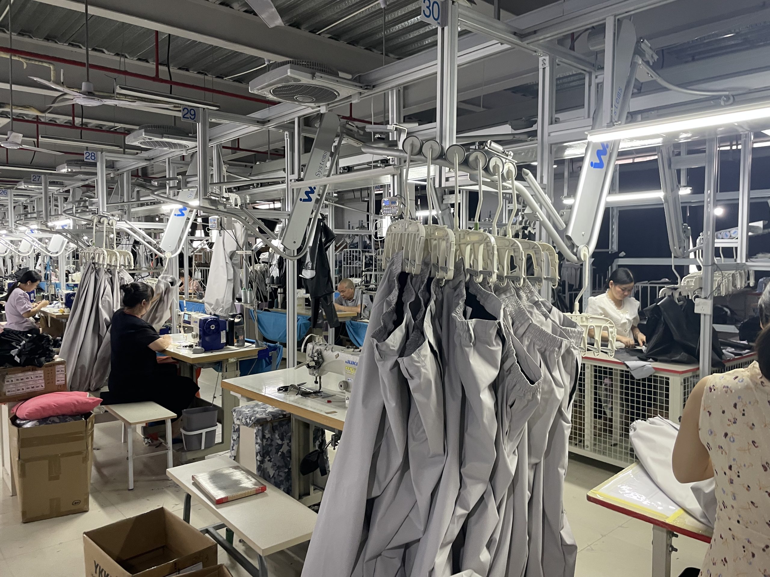 High-capacity automated garment production line featuring an advanced overhead hanger system, specializing in bulk OEM manufacturing of premium casual pants and denim.