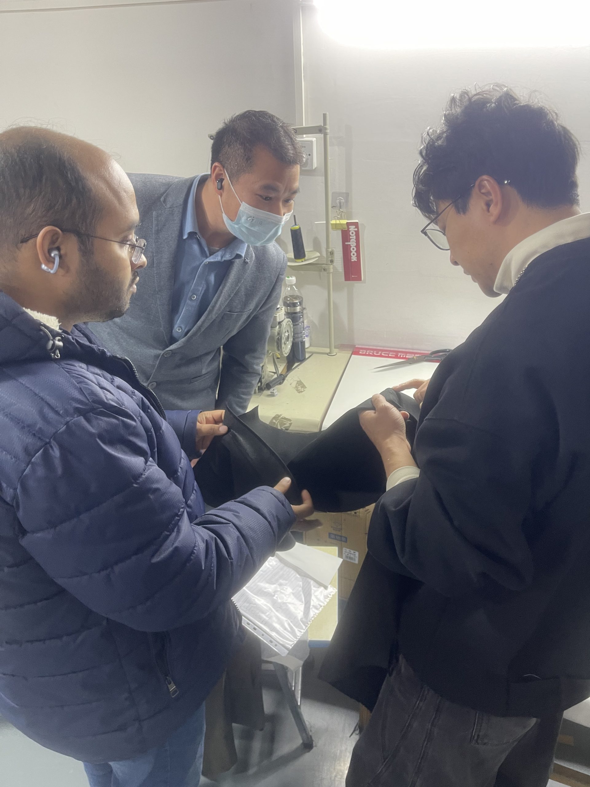 Professional sourcing team inspecting 11-14oz heavyweight denim fabric quality at our specialized garment factory